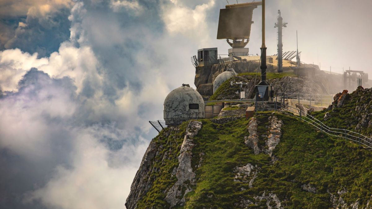 Dramatic mountain observatory with radar and clouds, offering a majestic aerial view.