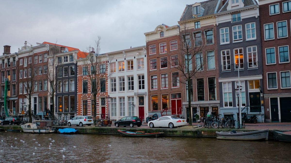 Picturesque view of traditional canal houses in Amsterdam with parked bikes and boats.