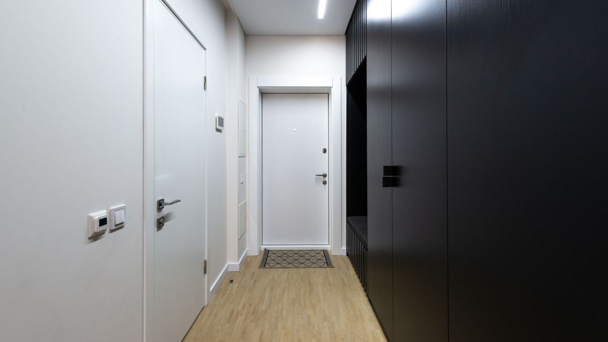 Interior of empty hallway with white doors and black wardrobe under luminous lamp on ceiling