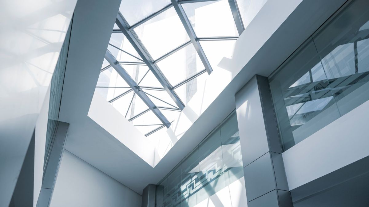 An interior look at a modern office building featuring a glass ceiling and sleek steel frames.