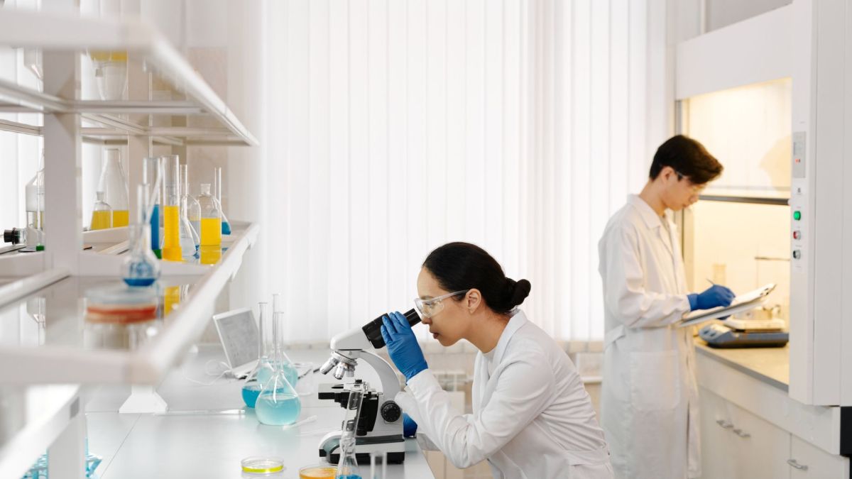 Two scientists working in a well-equipped laboratory with microscopes and test tubes.