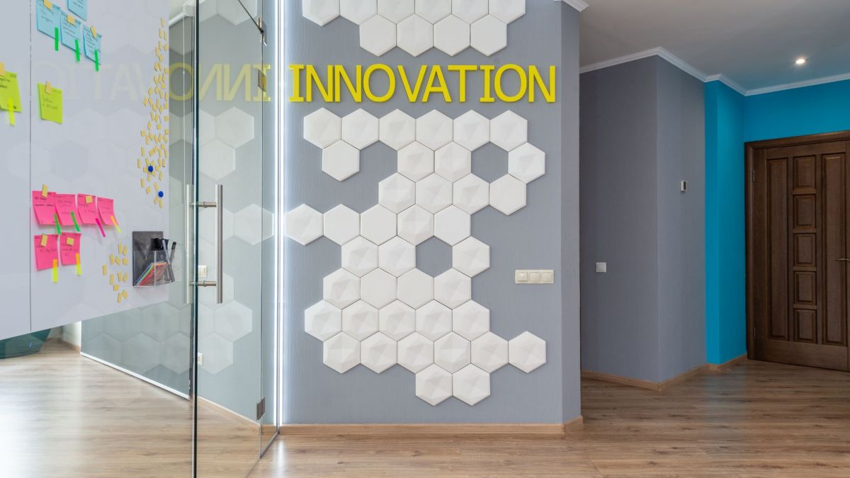Geometric decoration on wall with Innovation inscription near glass door of conference room with colorful stickers in hallway of office building
