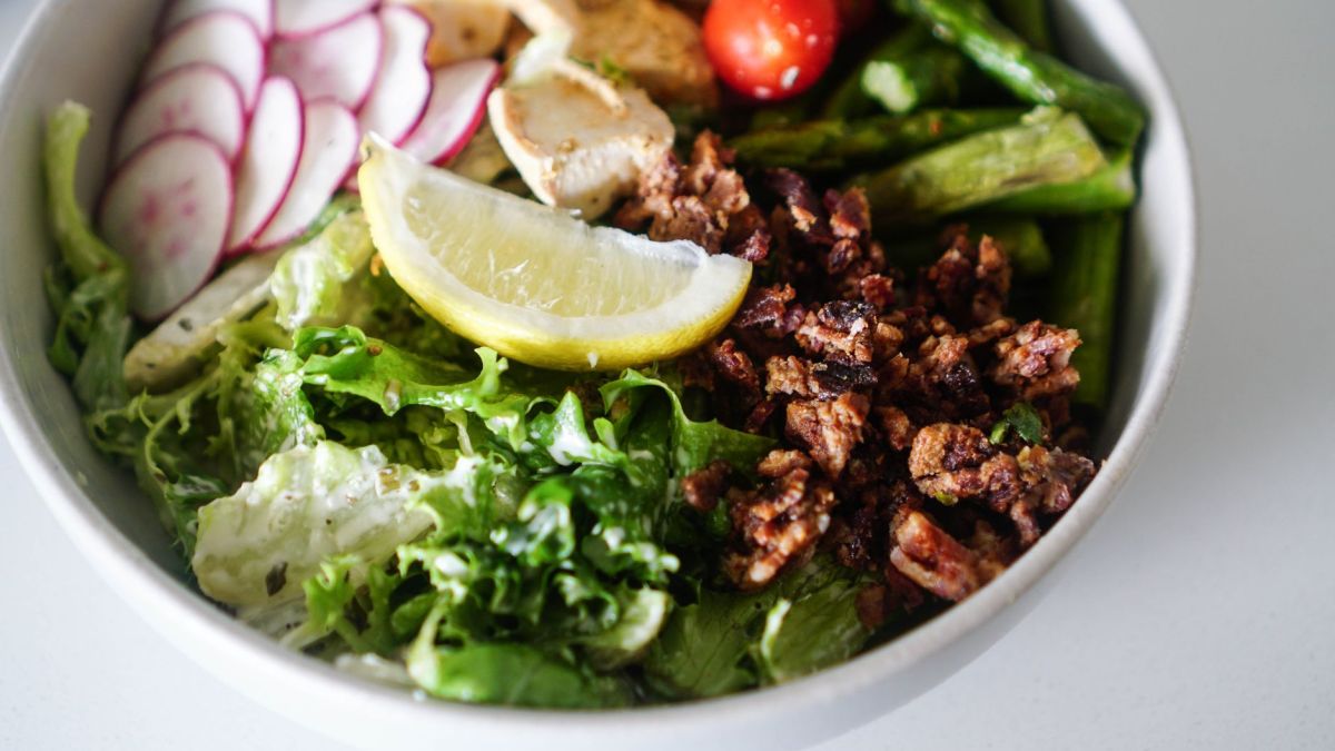 Delicious and vibrant salad bowl featuring fresh greens, chicken, and lemon slice.