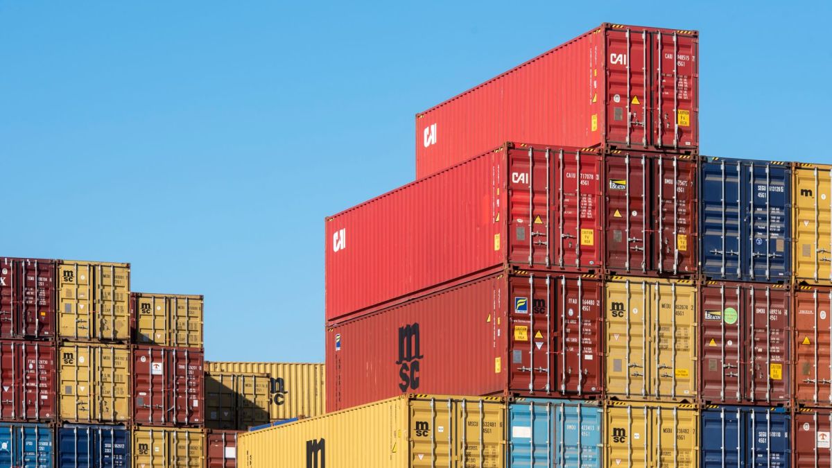 A vibrant collection of stacked shipping containers under a clear, blue sky. Ideal for logistic themes.