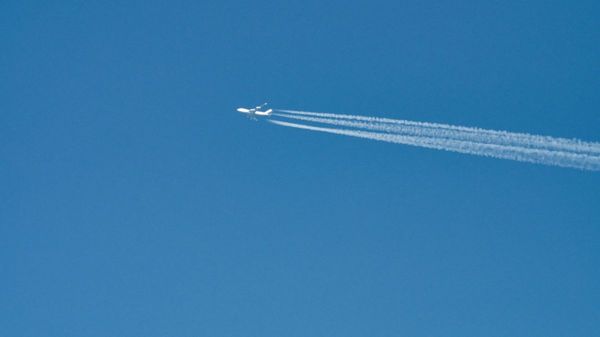 An airliner leaves a contrail against a bright blue sky over Poprad, Slovakia.