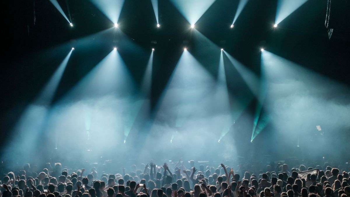 A dynamic concert scene with a large crowd enjoying vibrant stage lighting and a lively atmosphere.