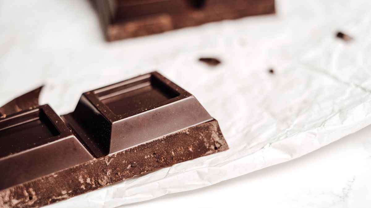 A close-up view of a dark chocolate bar placed on a crumpled wrapper, perfect for food-themed projects.