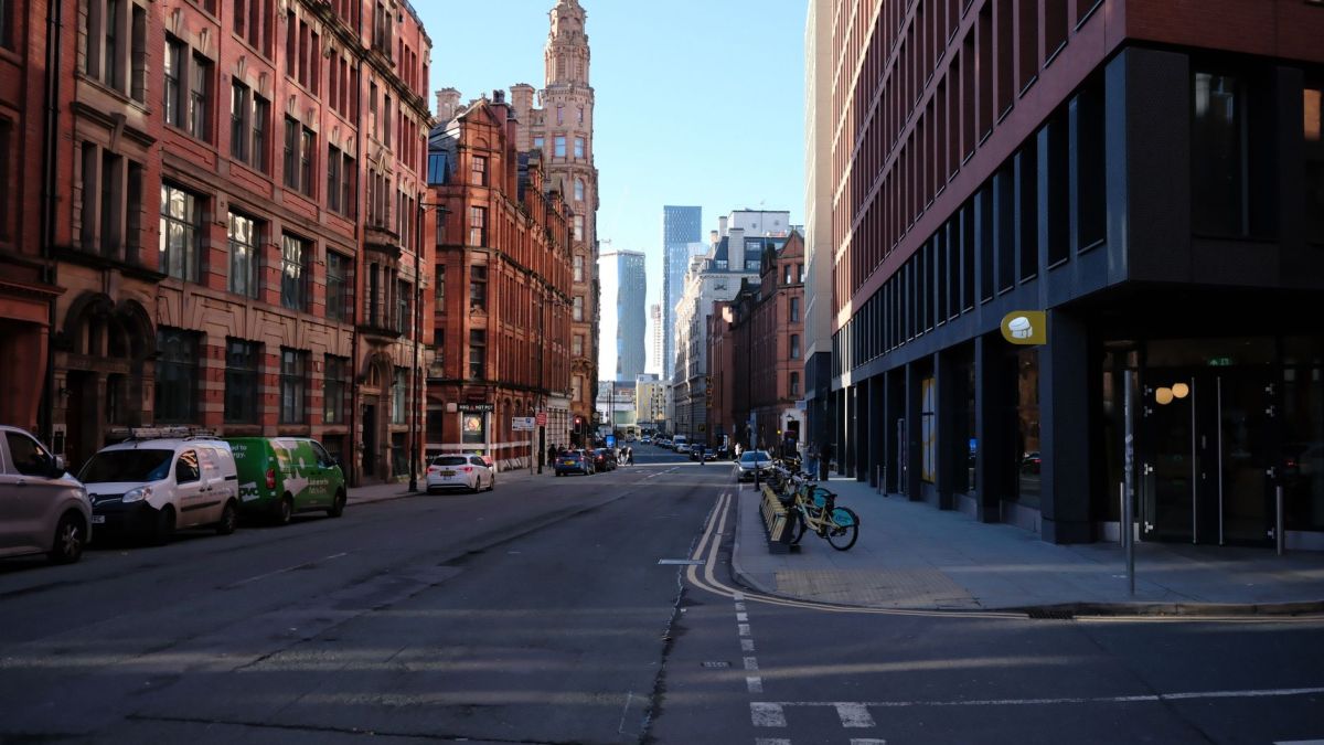 Urban streetscape in Manchester, showcasing modern and historic architecture under a clear blue sky.