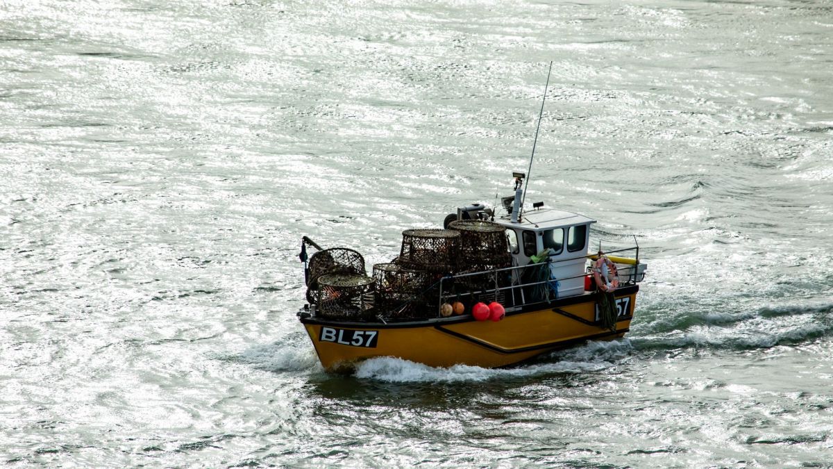 A fishing boat loaded with lobster pots navigates through the waters of Poole Harbour, England.