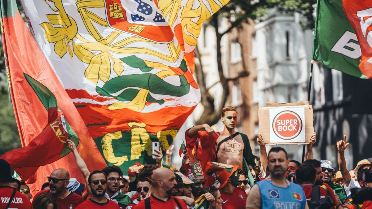Energetic crowd of Portuguese fans with flags cheering during street parade.