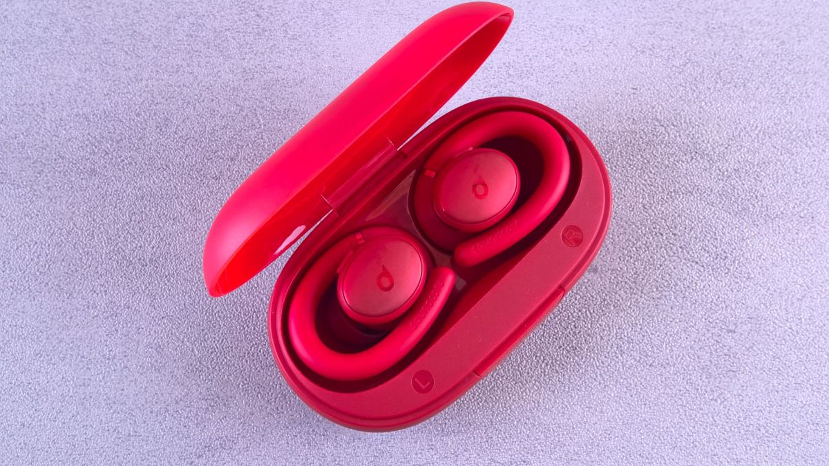 Top-down view of vibrant red wireless earbuds in an open charging case on a textured surface.