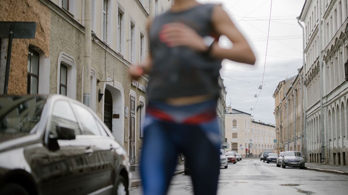A blurred runner in activewear dashes through a serene urban street, symbolizing vitality.