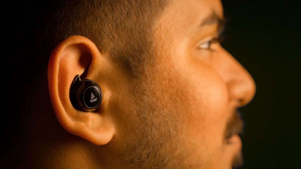 Profile view of a man wearing a wireless earbud, focusing on audio technology.
