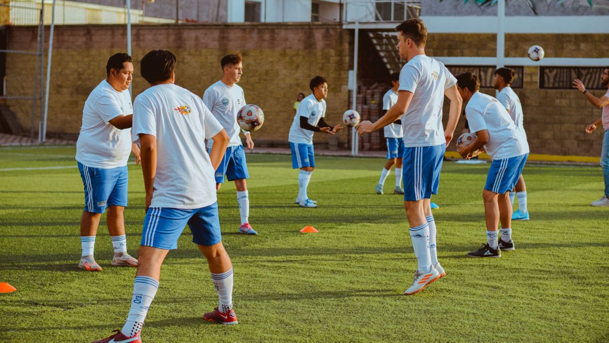 Dynamic image of a youth soccer team engaging in training drills on a sunny day.