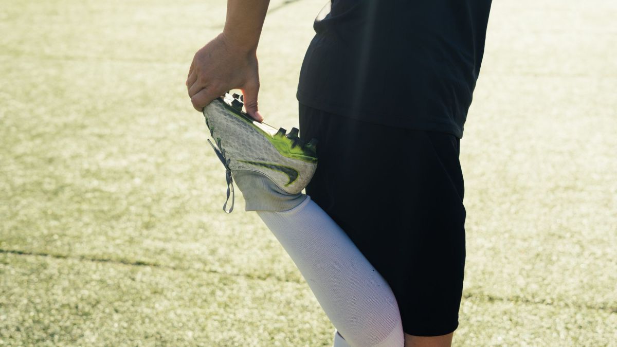 Athlete stretching before soccer practice on a sunny day outdoors.
