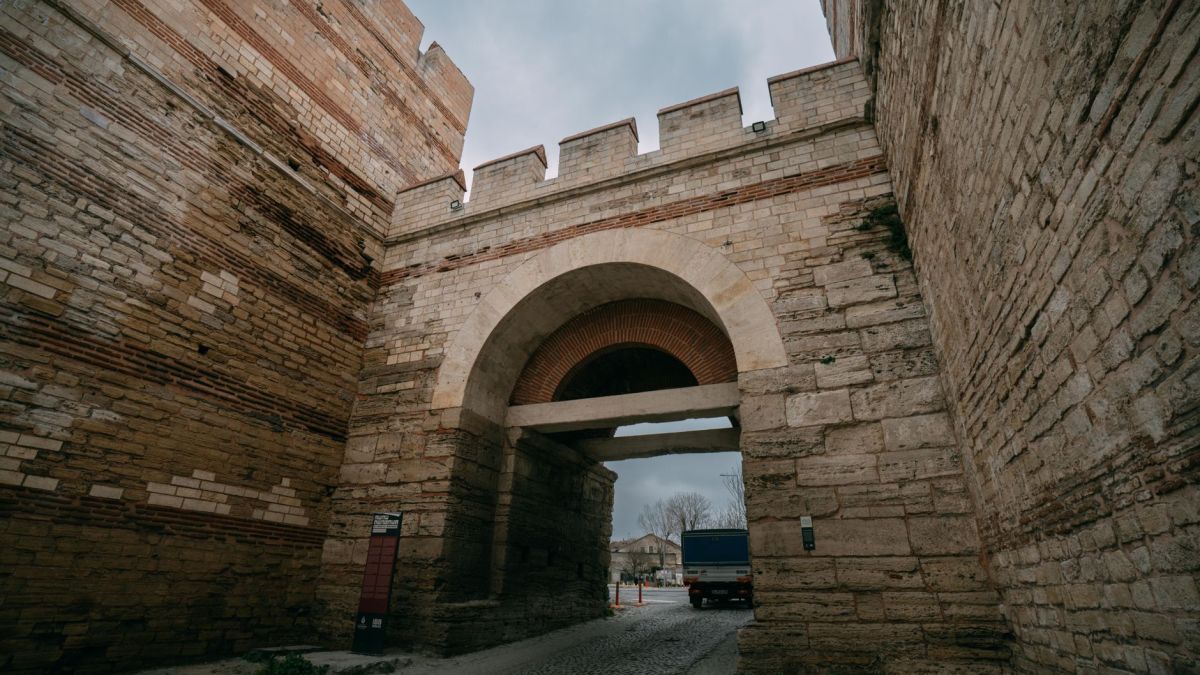 A massive stone gate of an ancient fortress captured from below on a cloudy day.