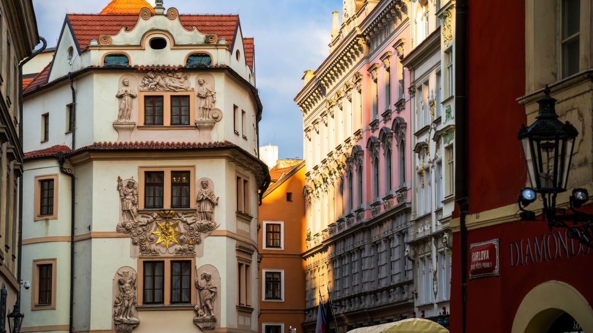 Charming street view of historic architecture in Prague city center, showcasing ornate facades in golden sunlight.